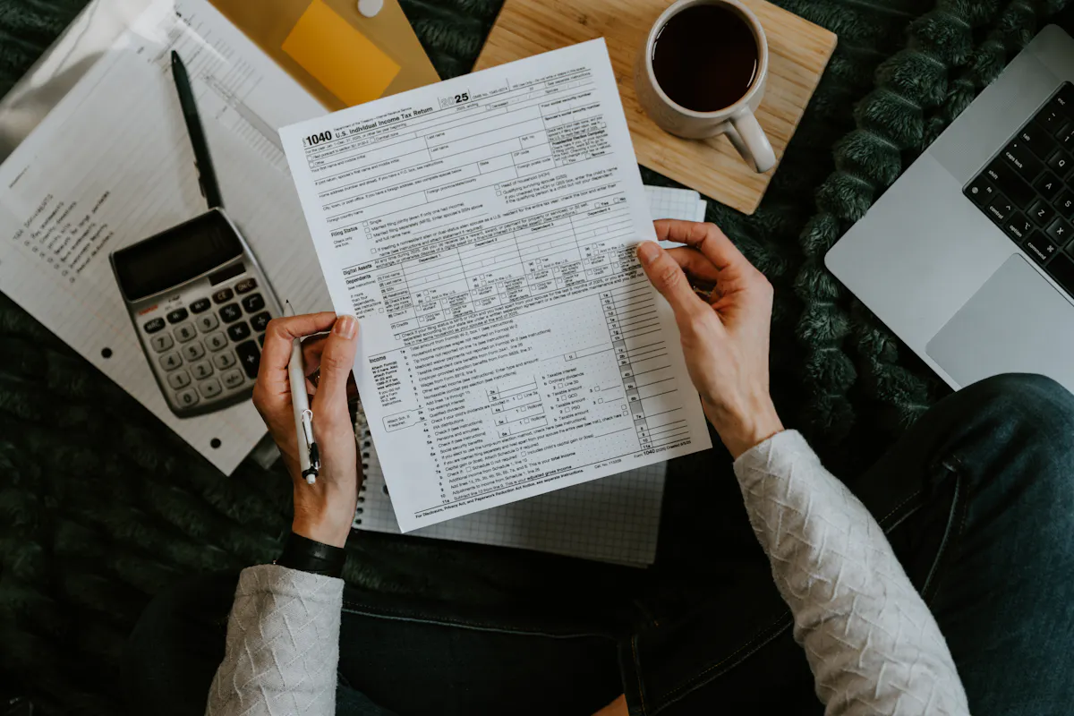 Hands holding claim paperwork with a calculator and laptop