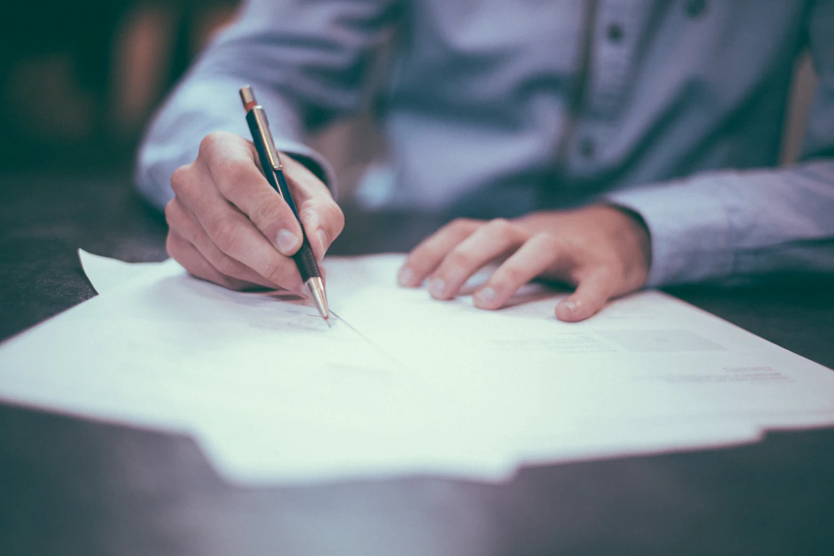 Hands signing claim documents with a pen