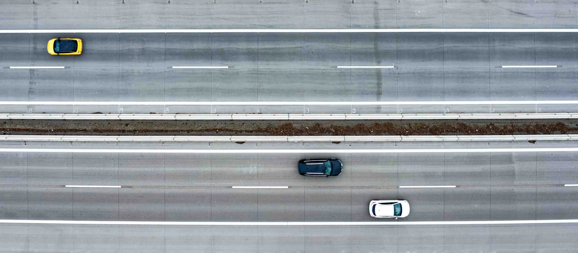 Cars travelling in separate lanes on a highway, seen from above
